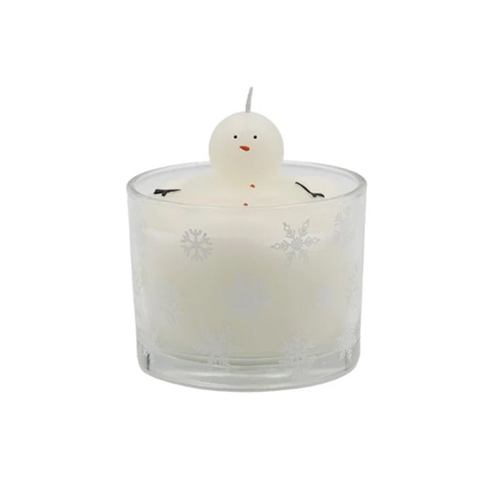 The Melting Snowman Candle features a snowman-shaped wax figure with a small face and twig-like arms in a clear glass holder topped with snowflakes—perfect for cozy winter decor.