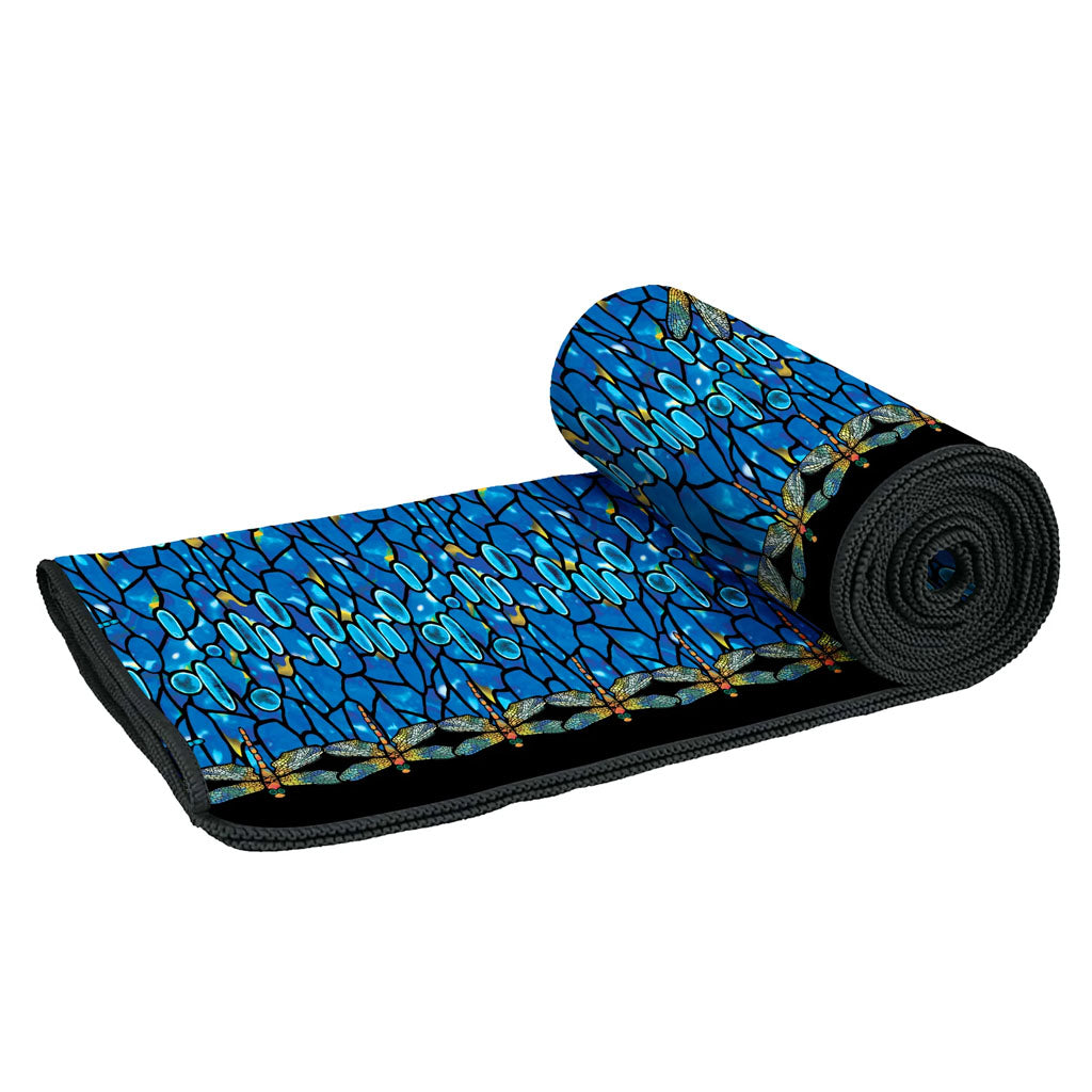 The Louis Comfort Tiffany Dragonfly Beach Towel features a vibrant blue geometric pattern and dragonfly designs along the edge, shown rolled up against a white background.