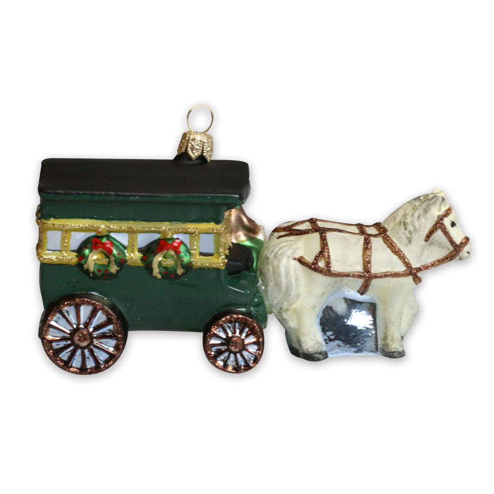 The Greenfield Village Carriage Ornament is a glass ornament shaped like a white horse pulling a green, gold, and black carriage with wreaths and large wheels—a perfect Michigan gift featuring a gold hanging loop.