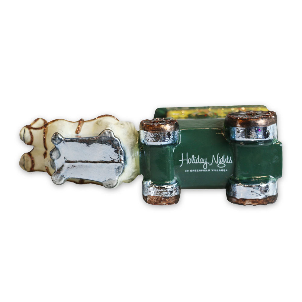 The Greenfield Village Carriage Ornament is a decorative ceramic figurine featuring a green vintage car with silver details and a beige reindeer—an ideal Michigan keepsake for collectors, marked with "Holiday Nights in Greenfield Village.