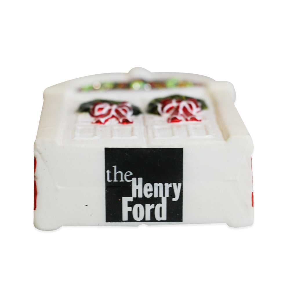 The Henry Ford Museum Festive Doors Ornament is a small white rectangle featuring two decorated doors and a black-and-white "the Henry Ford" label—a unique ornament perfect for fans of the Henry Ford Museum.