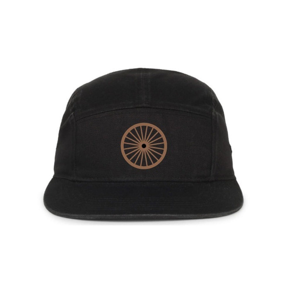 The Henry Ford® Bicycle Cap is a black five-panel cap featuring a brown circular wheel symbol on the front, inspired by classic cycling styles and shown against a white background.