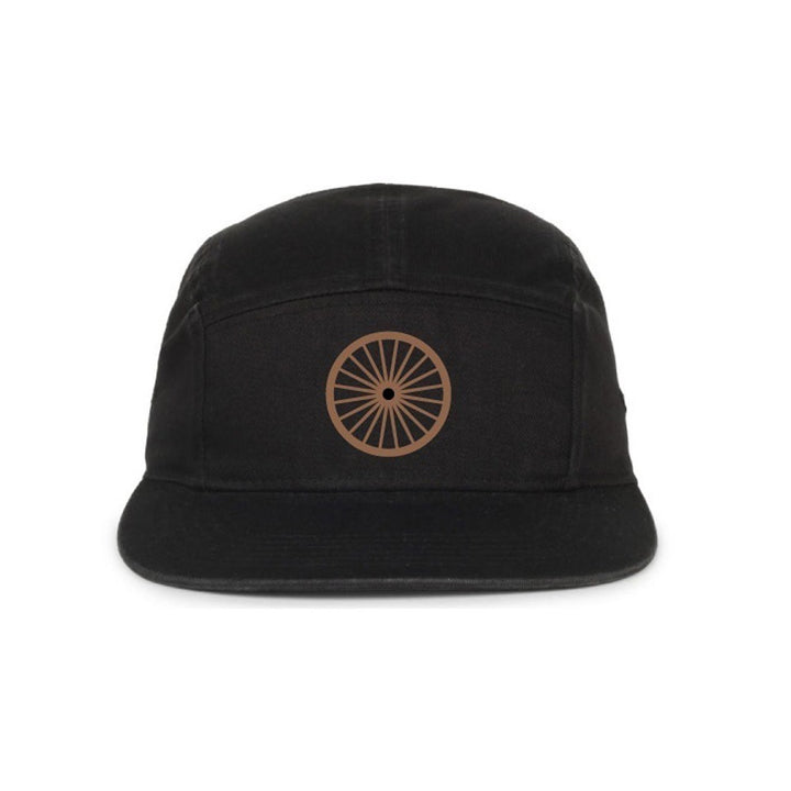 The Henry Ford® Bicycle Cap is a black five-panel cap featuring a brown circular wheel symbol on the front, inspired by classic cycling styles and shown against a white background.