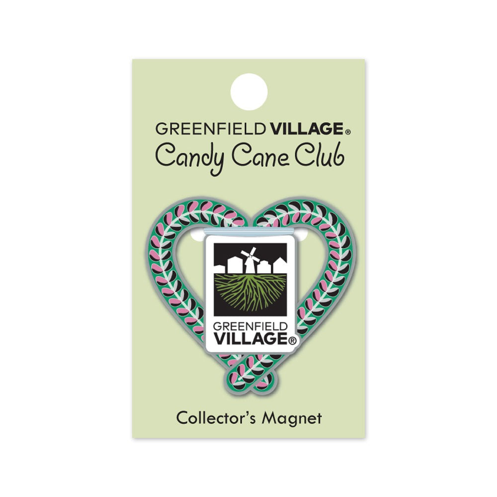 A heart-shaped magnet with pink and green stripes frames a barn, windmill, and fields badge. Titled The Henry Ford® Greenfield Village Candy Cane Charm Magnet—a sweet piece of collectible history.