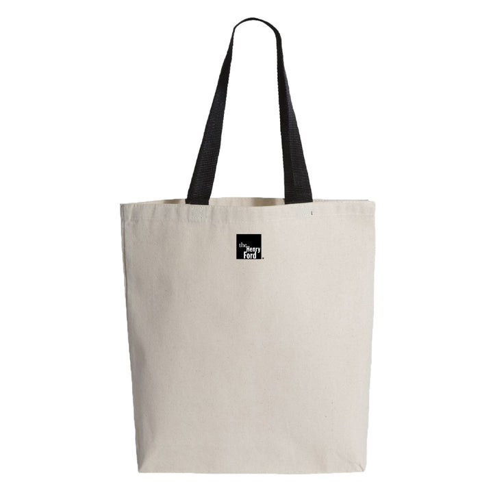 The Henry Ford® Rosa Parks Tote is an off-white canvas bag with two black handles and a black and white label reading "the every day tote" near the top center—perfect for everyday use.