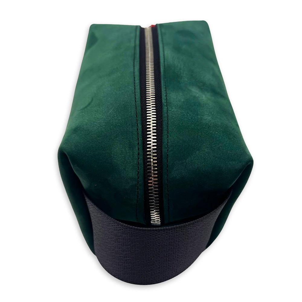 The Emerald Green Dopp Kit—a rectangular upcycled leather travel bag with a black base and silver top zipper, handcrafted in Detroit—is photographed from above on a white background. A sustainable accessory for any journey.