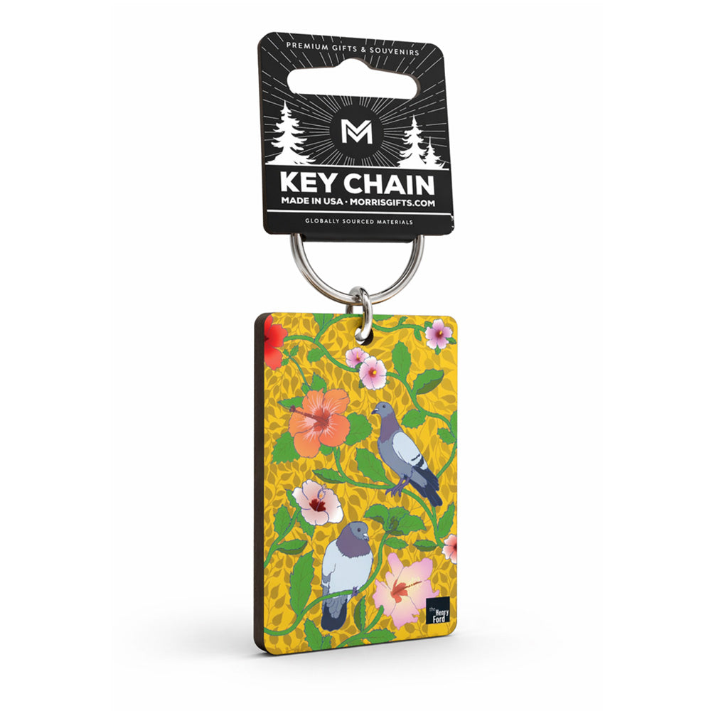 The Roberto Lugo Pigeon Art Keychain features two pigeons and tropical flowers on a yellow background, attached to a metal key ring with black "Key Chain" packaging. Available at The Henry Ford Museum.