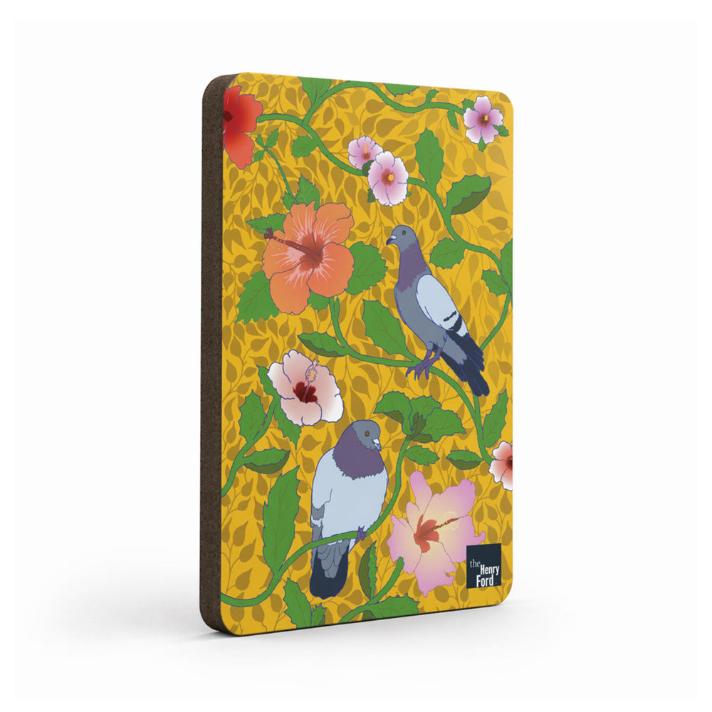 The Roberto Lugo Pigeon Art Magnet displays illustrated pink and red hibiscus flowers, green leaves, and two pigeons on a vibrant yellow background, inspired by the Hand Craft exhibit at Henry Ford Museum with the Henry Ford logo in the corner.