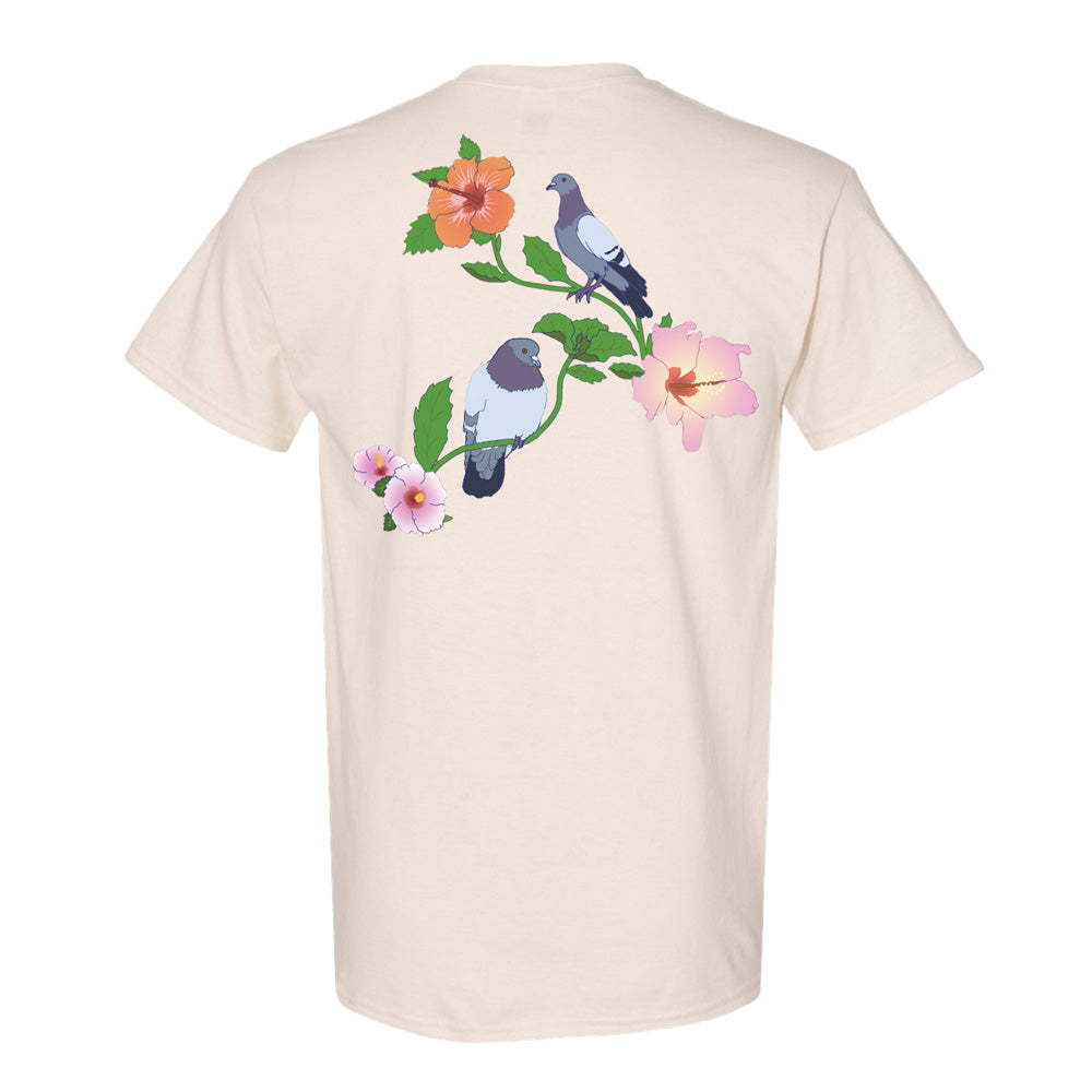 The Roberto Lugo Pleasant Pigeon T-Shirt is cream-colored with a back graphic of two pigeons on leafy branches and hibiscus flowers, inspired by the creative spirit at The Henry Ford Museum.