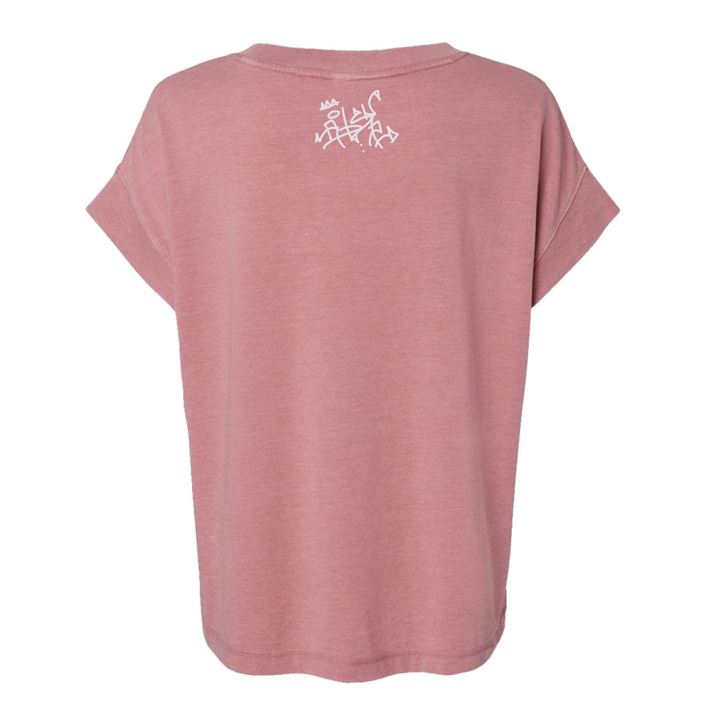 The Roberto Lugo Pretty Pigeon Women's T-Shirt is shown from the back in dusty pink, featuring a white graffiti-style design near the neckline. It has soft fabric, a relaxed fit, and rolled sleeves, inspired by Roberto Lugo’s Hand Craft exhibit.