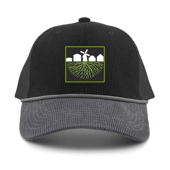 The Greenfield Village Corduroy Trucker Cap features a black and gray mesh design with a front patch depicting white houses, a windmill, and green roots—a tribute to the picturesque landscape of Greenfield Village, the renowned living history museum.