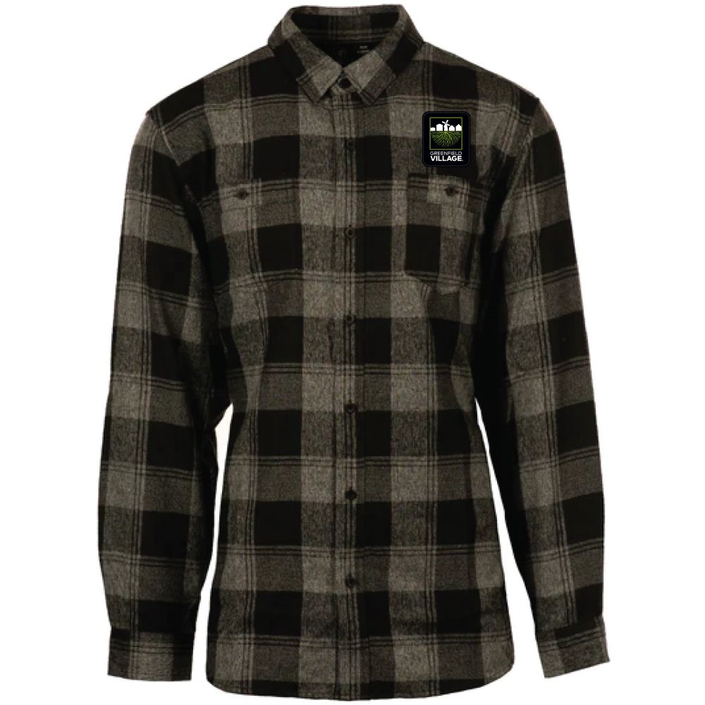 Green and gray plaid flannel button-up shirt with collar and chest pockets. A small rectangular patch featuring a logo and the word “VILLAGE” is sewn onto the left chest, adding a unique detail to the Greenfield Village Flannel T-Shirt. The shirt is displayed against a white background.