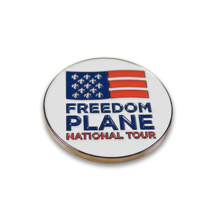 The Freedom Plane Tour Coin features a round design with a stylized American flag above the words FREEDOM PLANE NATIONAL TOUR on white—ideal for history collectors or as a National Archives tour keepsake.