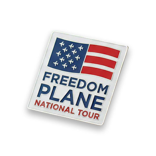 The Freedom Plane Tour Lapel Pin is a square pin featuring a stylized red and blue American flag with airplane icons as stars and the text “FREEDOM PLANE NATIONAL TOUR” in bold blue and red below the flag.