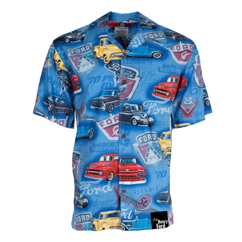 The Ford Logo Truck Camp Shirt is a blue short-sleeve button-up shirt showcasing classic Ford trucks, vintage Ford logos, and automotive designs in red, yellow, black, and blue on a patterned background.