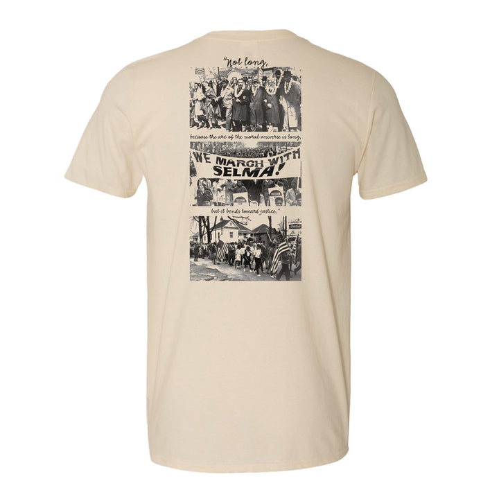 The Greenfield Village Selma How Long History T-Shirt features black-and-white images of historic civil rights marches, a WE MARCH WITH SELMA! banner, and a quote from Martin Luther King Jr.: “Not long, because the arc of the moral universe is long.”.