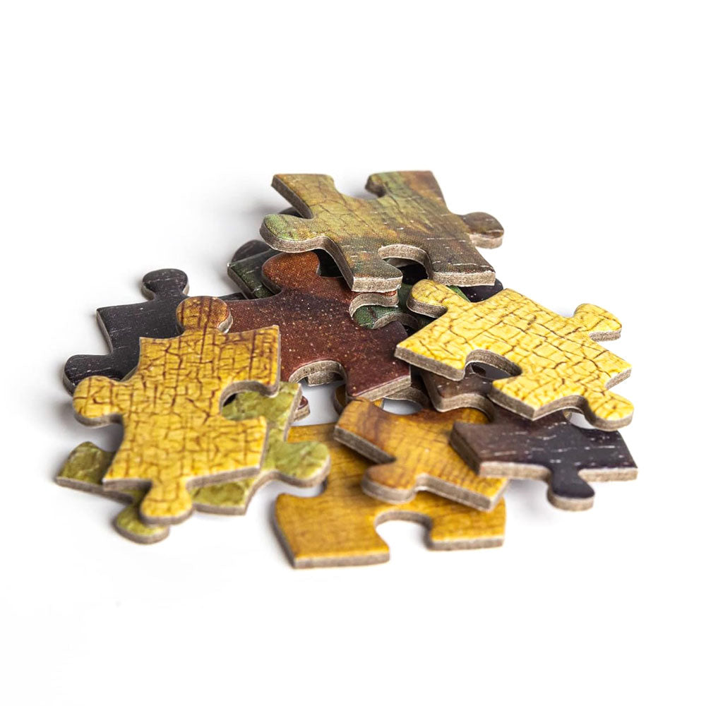 A small pile of assorted jigsaw pieces with yellow, brown, and green patterns from the 1000-piece Leonardo Da Vinci - Mona Lisa Puzzle sits on a white background.