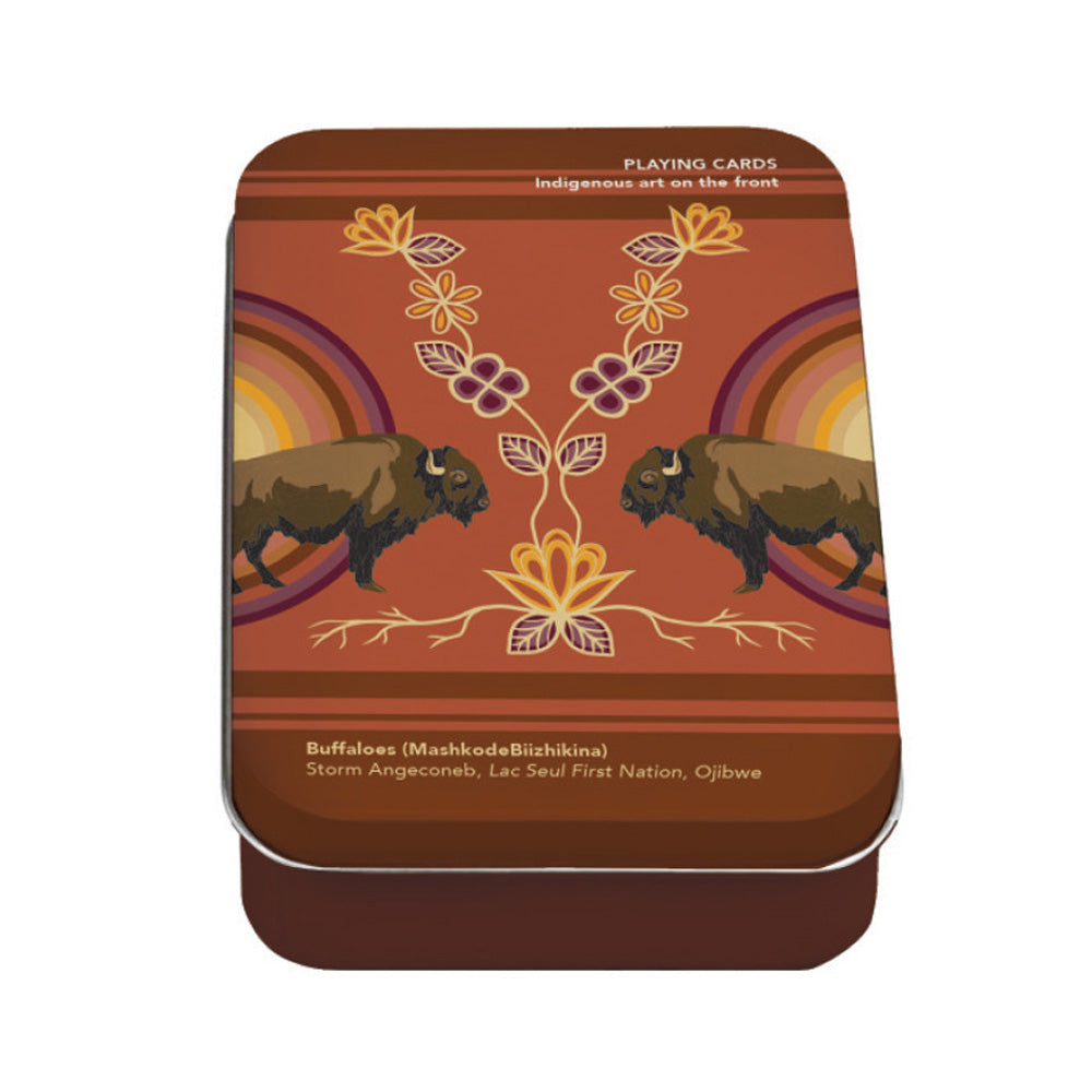 The Native Northwest Buffaloes Playing Cards come in a rectangular tin adorned with Indigenous artwork of two buffalo, floral designs, and vibrant patterns. The text includes "Buffaloes (MashkodeBizhikiina)" and acknowledges Ojibwe Nation artists.