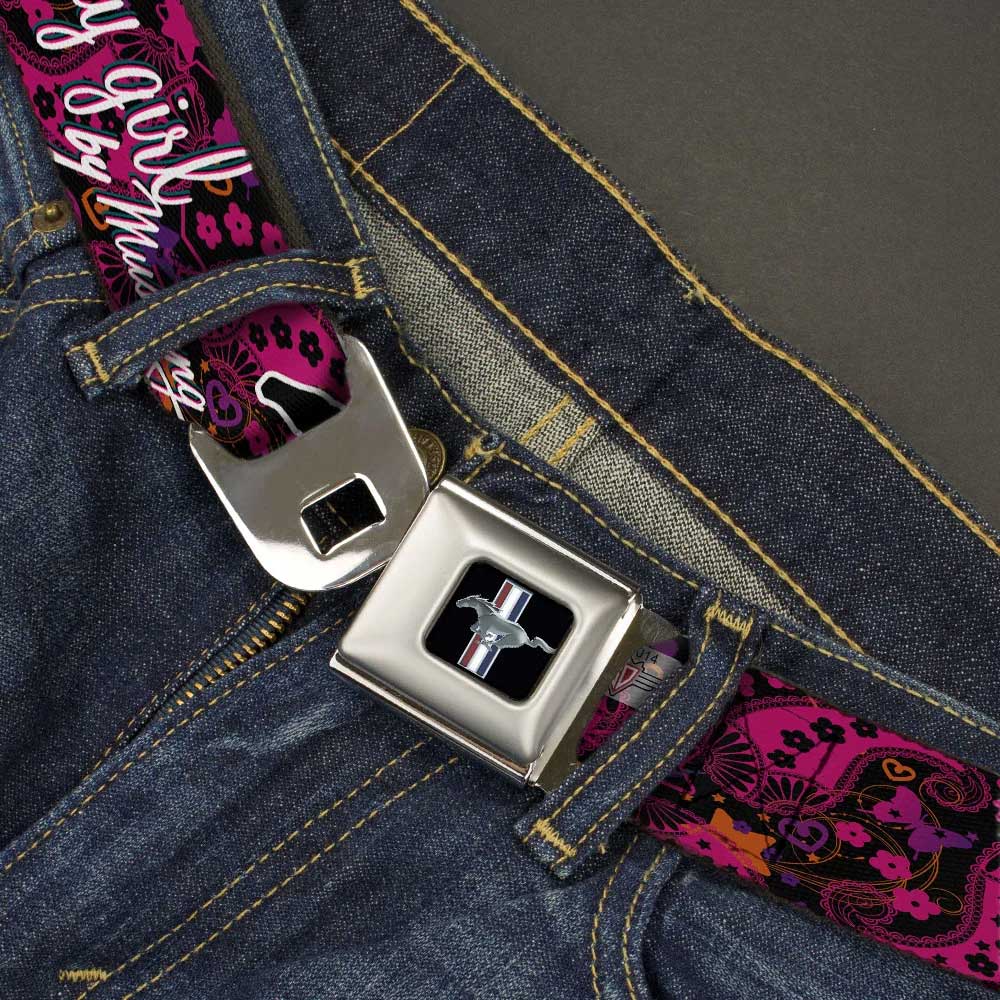Close-up of blue jeans featuring the Ford Mustang Emblem Ladies Seatbelt Belt—an eye-catching accessory with a colorful, patterned pink design, floral details, and car logo, perfect for any Mustang enthusiast.