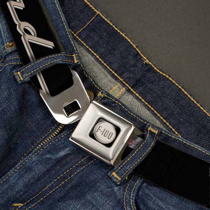 A close-up of blue jeans with the Ford F-100 Logo Seatbelt Belt, featuring an automotive buckle design and a shiny, metal airplane seat belt-style clasp.