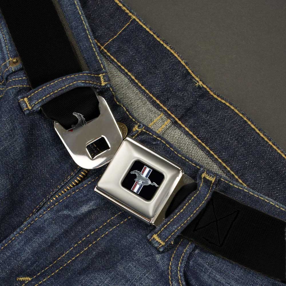 A close-up of blue jeans with the Ford Mustang Emblem Seatbelt Belt, a distinctive automotive fashion accessory designed to resemble a car seatbelt and featuring a silver buckle adorned with the iconic Mustang emblem. This unique belt effortlessly combines stylish appeal with auto-inspired flair.