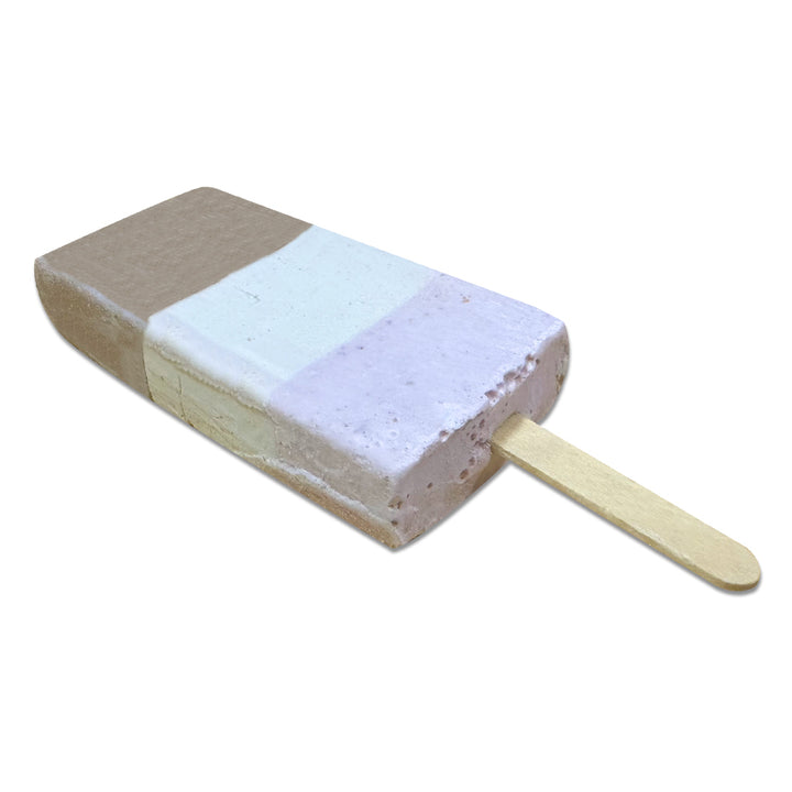 Introducing Space Pops Freeze Dried Neopolitan Ice Creamy Pops: a space-themed treat on a wooden stick, featuring three distinctive layers—brown (chocolate), white (vanilla), and pink (strawberry)—captured in a freeze-dried bar and isolated on a white background.