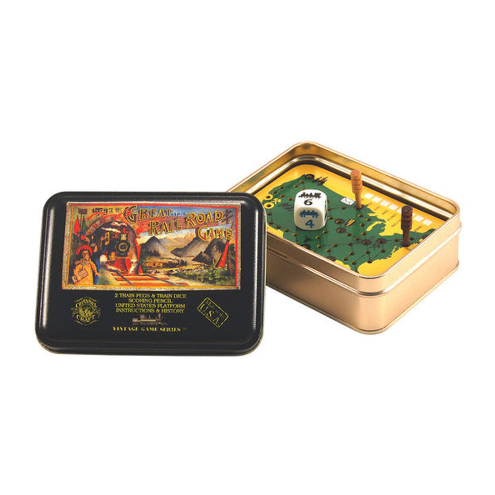A travel-size Great Railroad Game Tin sits open, displaying a game board inside along with a die and two wooden pegs. The tin’s lid, adorned with vintage Victorian-era tabletop game artwork, rests beside it.