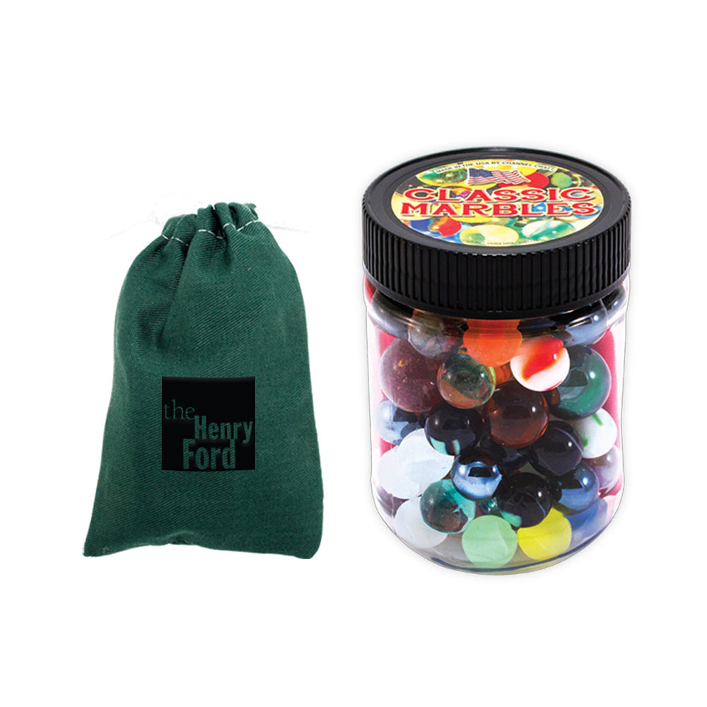 A green drawstring bag labeled The Henry Ford sits next to a clear jar with a black lid, filled with colorful Classic Marbles—ideal for marble games and improving hand-eye coordination.