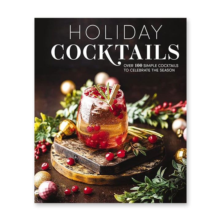 A festive cocktail with cranberries, rosemary, and cinnamon sits on a wooden coaster amid holiday greenery. At the top, the book "Holiday Cocktails: Over 100 Simple Cocktails to Celebrate the Season" is featured for Christmas party drinks.