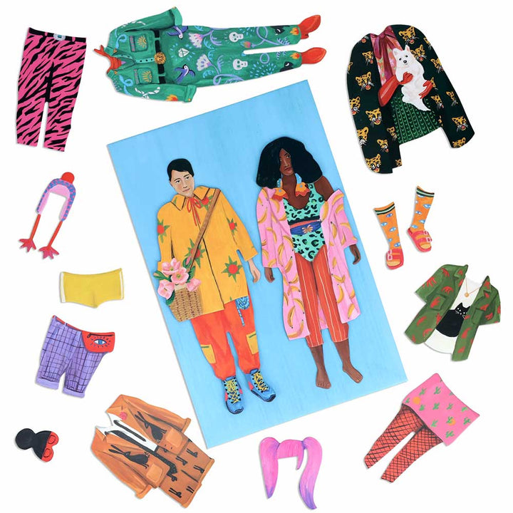 Fearless Fashion Magnetic Dolls features a man and woman in vibrant outfits, surrounded by mix-and-match jackets, pants, socks, hats, shorts, and wigs—all displayed on a white background.