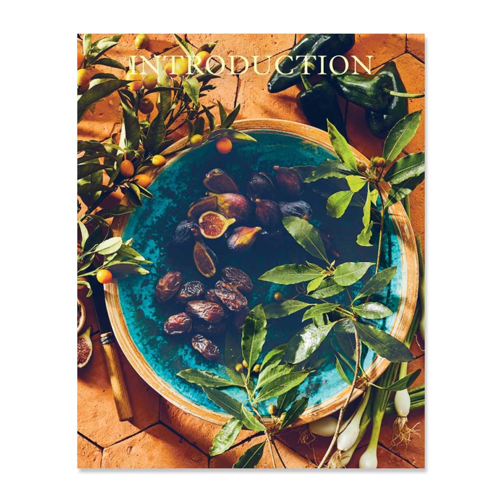 A blue bowl with figs and dates sits on terracotta tiles, surrounded by leafy branches, yellow fruit, and green onions—offering a vibrant look into modern soul food. “INTRODUCTION” appears above the cover of Tanya Holland's California Soul.