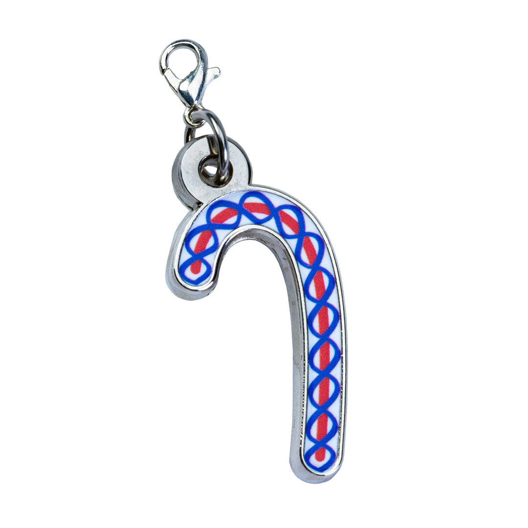The Henry Ford® Greenfield Village Candy Cane Charm is a metal keychain shaped like a candy cane, adorned with a repeating red and blue geometric pattern. It features a silver clasp at the top for easy attachment and makes the perfect festive Christmas keepsake from Greenfield Village. Displayed on a white background.