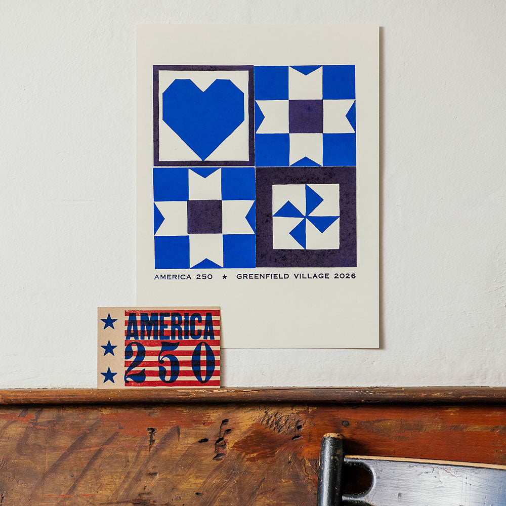 The America 250 Postcard features blue and white geometric quilt patterns with “AMERICA 250 GREENFIELD VILLAGE 2026,” capturing the spirit of America's anniversary—just like a Liberty Craftworks note on brown kraft paper.