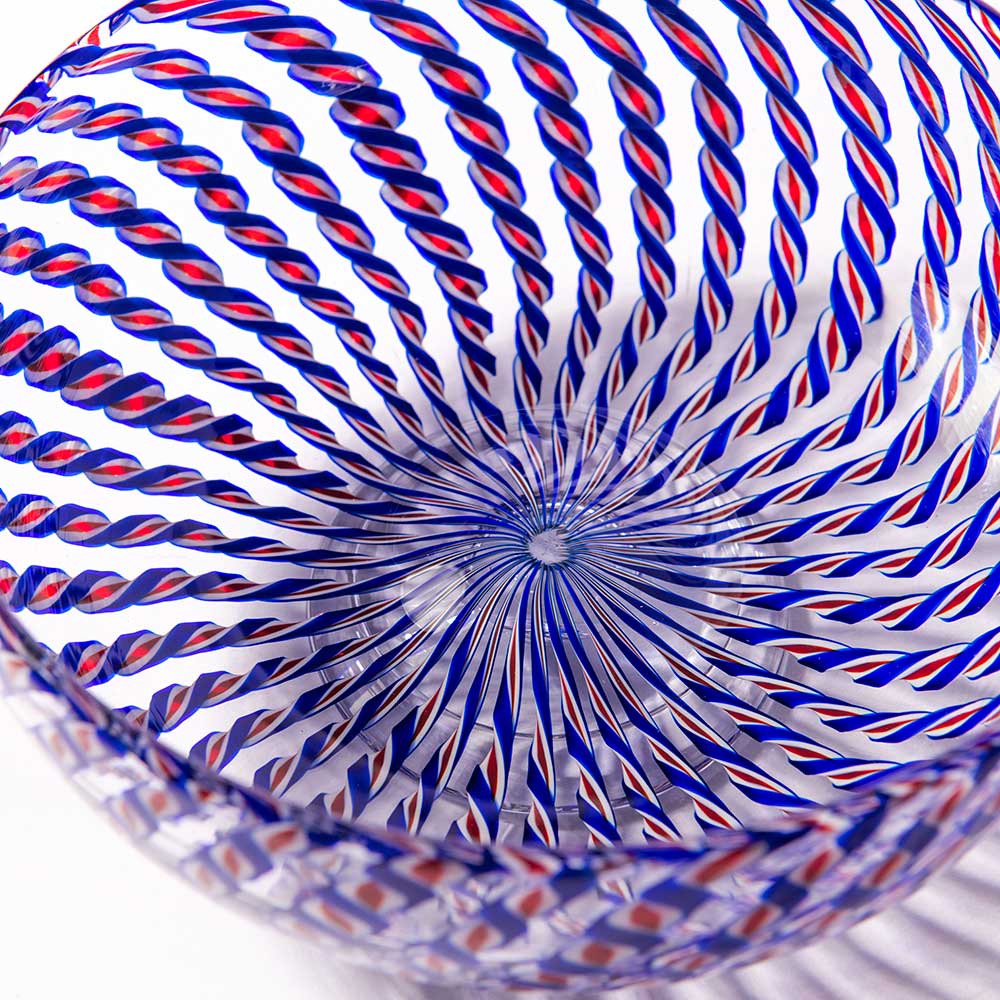 A close-up of the 2026 Candy Cane Bowl, expertly crafted by glassblowers, showcases swirling blue and red twisted stripes forming a mesmerizing spiral that converges at the bowl’s center.