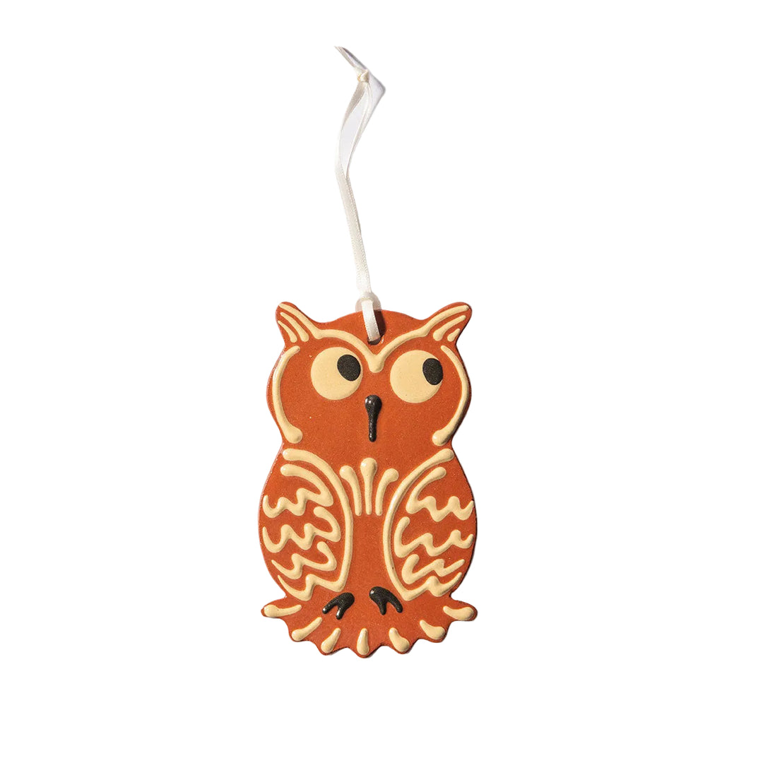 A flat, slip-decorated Redware Owl Ornament shaped like an owl, featuring white icing details and a white ribbon for hanging, photographed on a plain white background—perfect for adding handmade charm to your Hallowe’en 2026 celebrations.