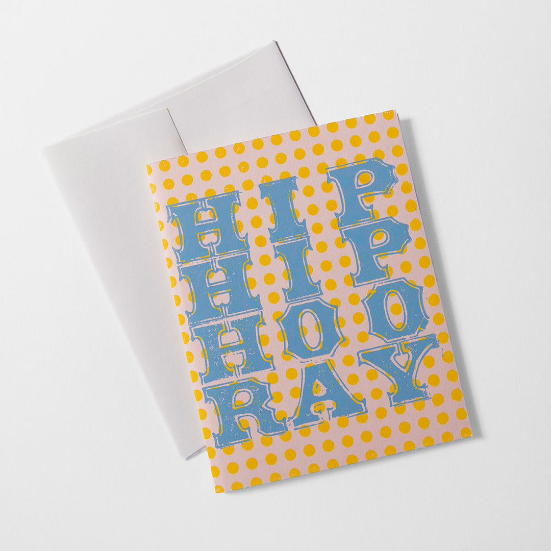 The Hip Hip Hooray Card features bold blue “HIP HIP HOORAY” text on a yellow polka-dot background, displayed with a white envelope and crafted by Liberty Craftworks.