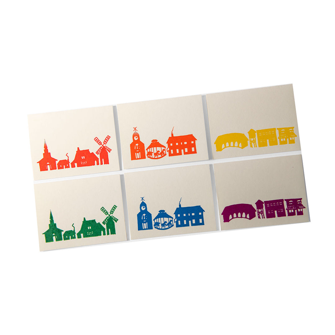 The Rainbow Village Card Set of 6 features rectangular cards with colorful silhouettes of Greenfield Village landmarks in green, red, blue, orange, yellow, and purple—printed with photopolymer plates on an 1880s treadle press.