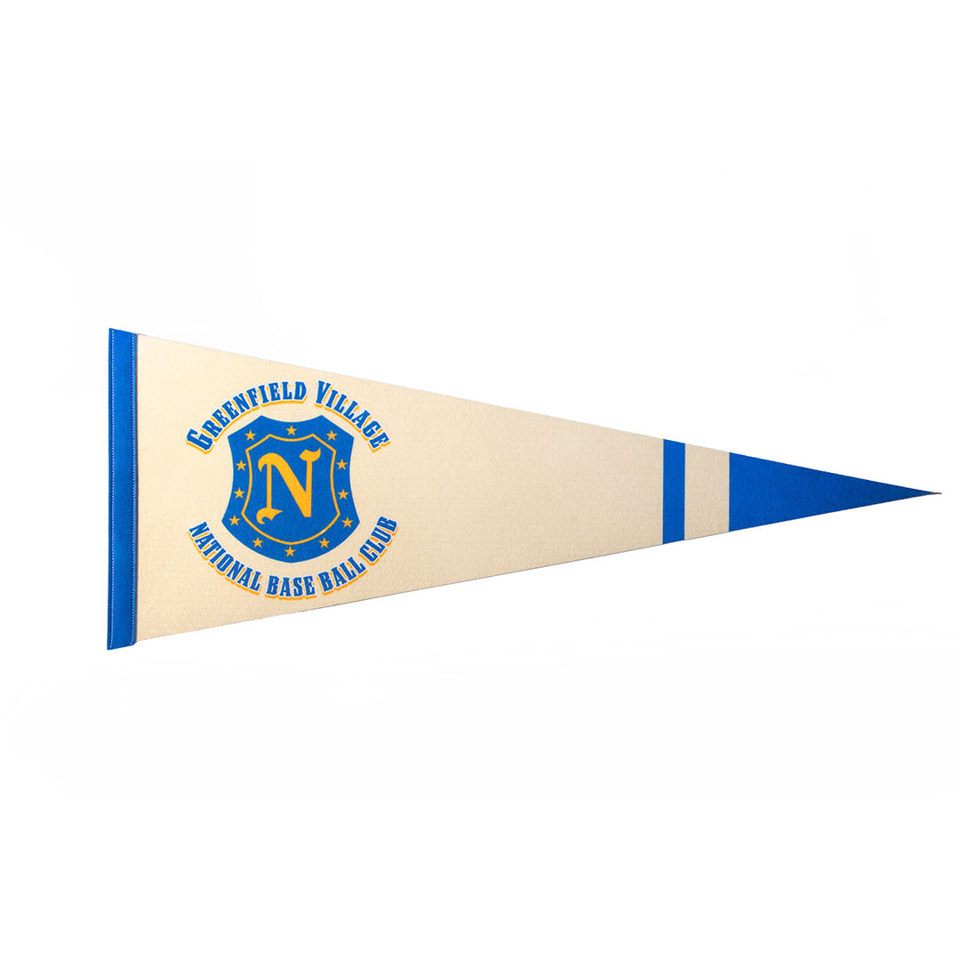 A cream and blue vintage Greenfield Village Base Ball Club Pennant with “Deerfield Village National Base Ball Club” around a blue and yellow N crest, stars, and a baseball makes a unique collectible on a white background.