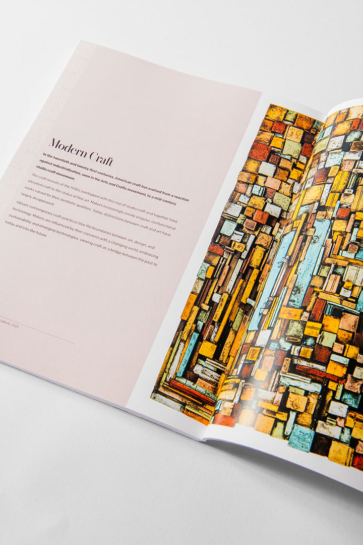 An open magazine displays a page with the heading “Modern Craft” on a pale pink background, while the opposite page features a vibrant geometric artwork composed of yellow, orange, and teal rectangles. This layout reflects the essence of The Henry Ford’s Fabric of America and Handmade Exhibition Catalog, celebrating modern American craftsmanship and artifacts.