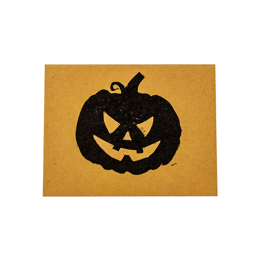 A hand-carved black ink block print of a scary-cute jack-o-lantern on a Pumpkin Halloween Card.