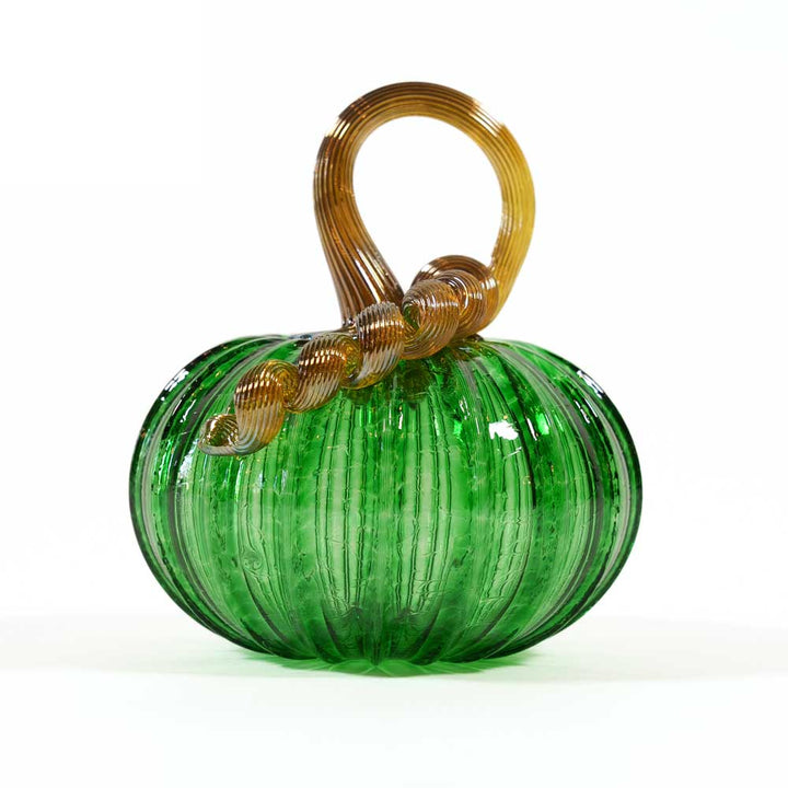 The Small Glass Pumpkin - Kelly Green is a collectible keepsake, hand-blown with green vertical ridges and a twisted brown stem, beautifully displayed on white. Inspired by the artistry of Greenfield Village.