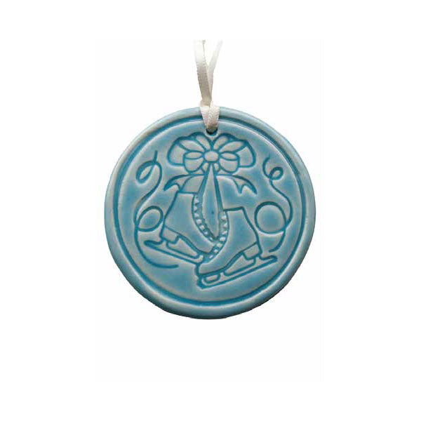 The Limited Edition Ice Skates Ornament is a round blue porcelain collectible featuring raised ice skates tied with a bow, hanging from a white ribbon, and inspired by Greenfield Village.