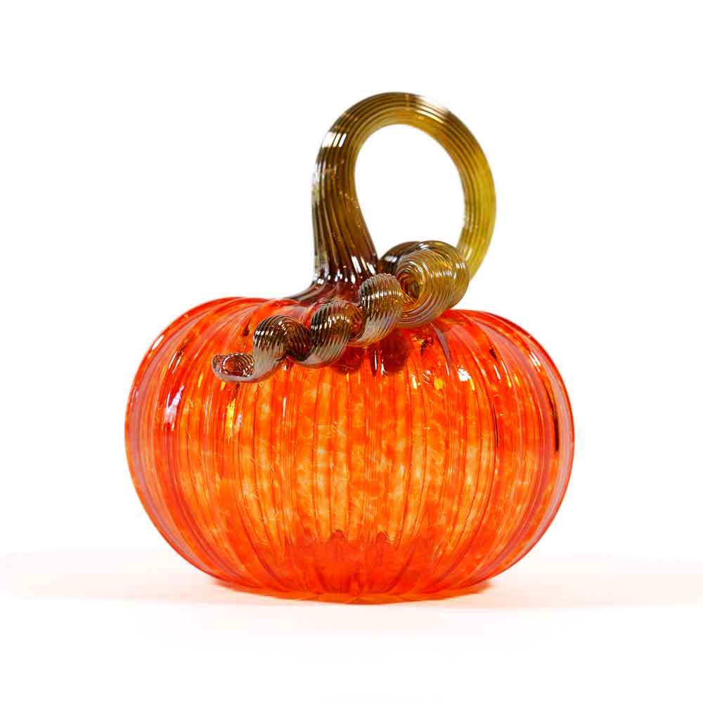 Introducing the Small Glass Pumpkin - Orange: a shiny, hand-blown glass pumpkin featuring a vibrant orange color, ribbed texture, and a curly brown glass stem on top. This collectible keepsake evokes the charm of Greenfield Village and is beautifully showcased against a pristine white background.