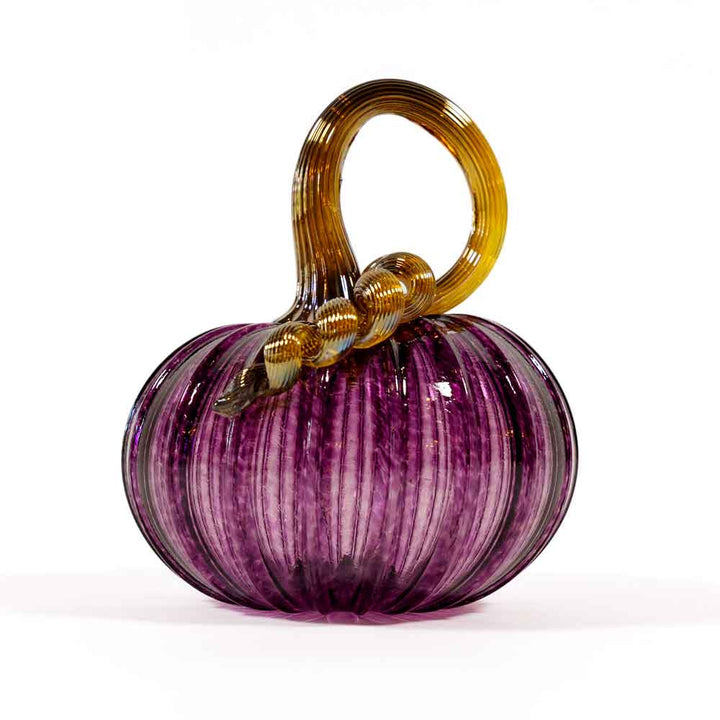 The Small Glass Pumpkin - Purple features a hand-blown, ribbed translucent purple body and a twisted golden-brown stem, making it a charming collectible keepsake inspired by Greenfield Village.