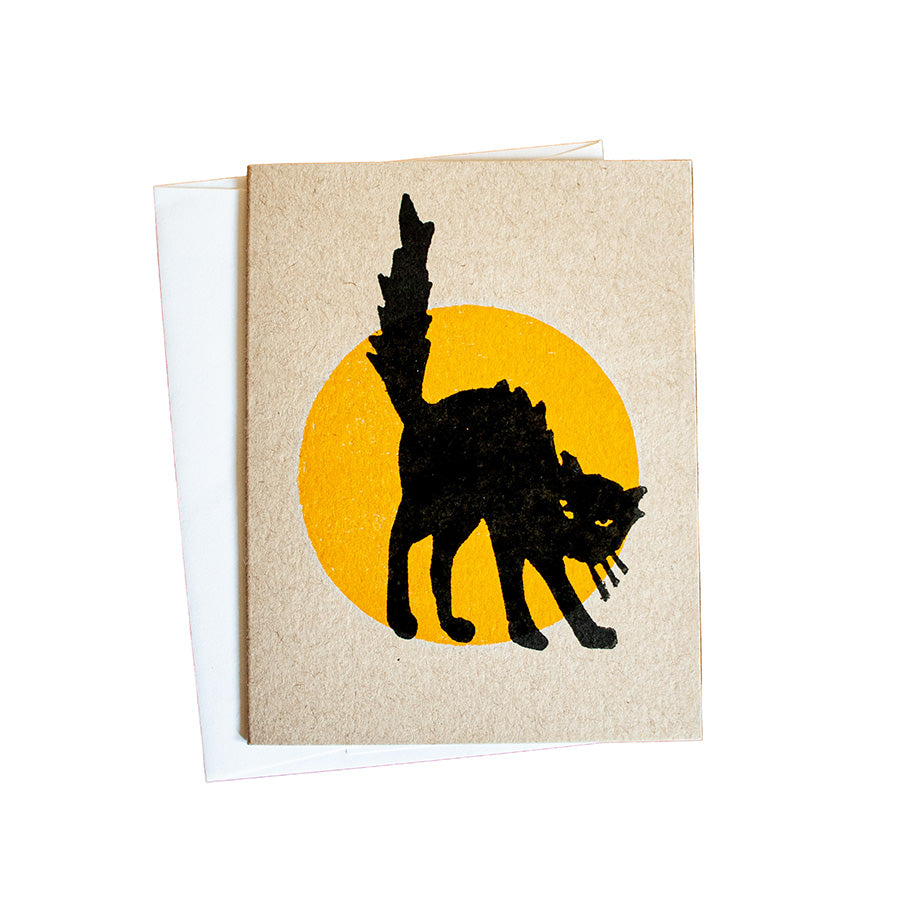The Black Cat Halloween Card features a black cat arching its back before a yellow circle on a white background—perfect for fans of hand-carved designs or those who love Greenfield Village charm.