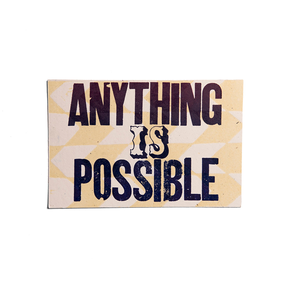 The Anything is Possible Postcard features "ANYTHING IS POSSIBLE" in bold dark letters on a light geometric background, inspired by vintage letterpress postcards. The word "IS" stands out in a decorative font.