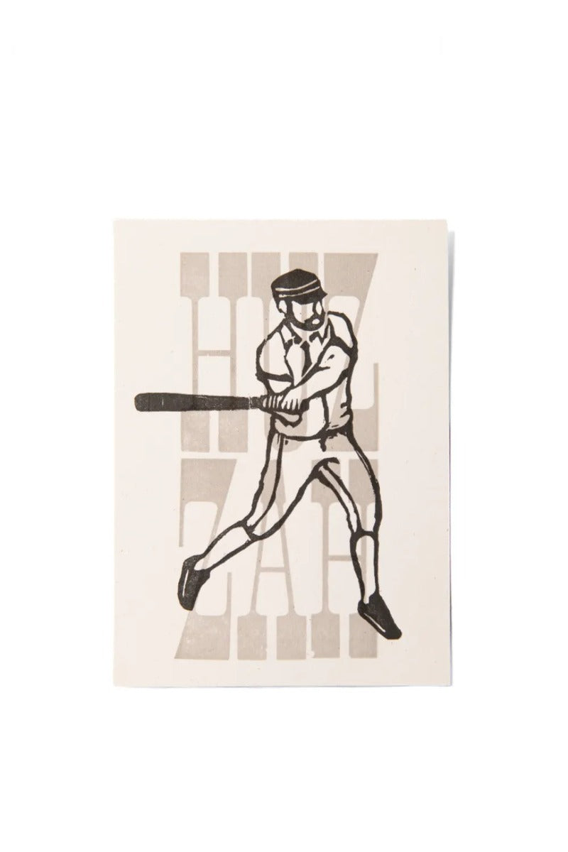 Black and white illustration of a baseball player swinging a bat with the large, faded word "HUZZAH" in William Page wood type on a white rectangular card—evoking a vintage base ball poster. Huzzah Mini Poster.