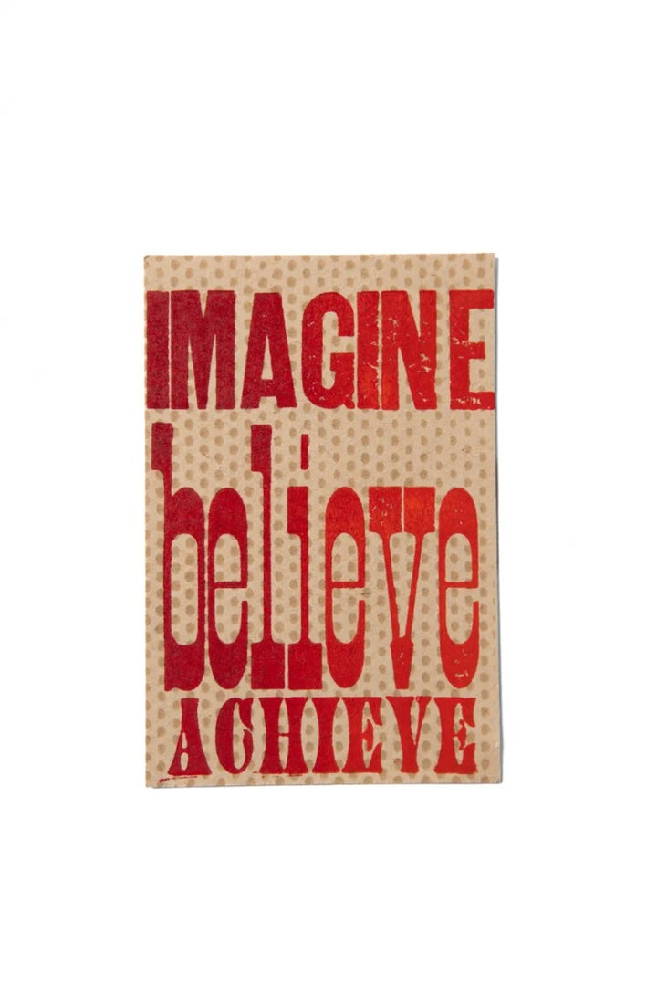 The Imagine Believe Achieve Postcard features the words IMAGINE, BELIEVE, and ACHIEVE in bold red on a beige background, styled like antique wood type letterpress for a textured motivational look.