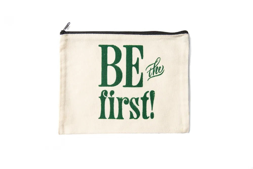 The Be the First Pouch is a cream canvas zip-top bag with "BE the first!" in bold green letters, inspired by Greenfield Village Print Shop—ideal for carrying art supplies.