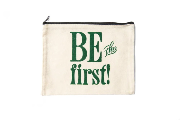 The Be the First Pouch is a cream canvas zip-top bag with "BE the first!" in bold green letters, inspired by Greenfield Village Print Shop—ideal for carrying art supplies.